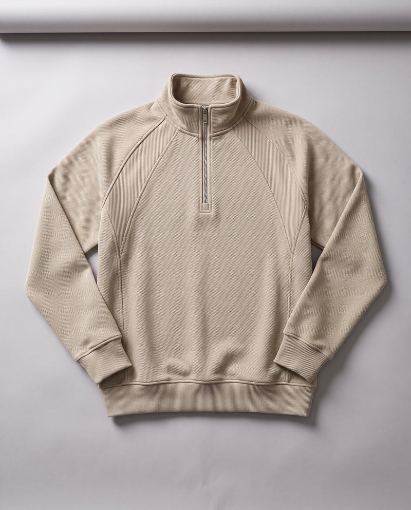 Sweat beige sable à demi-zip présenté à plat, entièrement déplié, avec col montant et fermeture éclair.