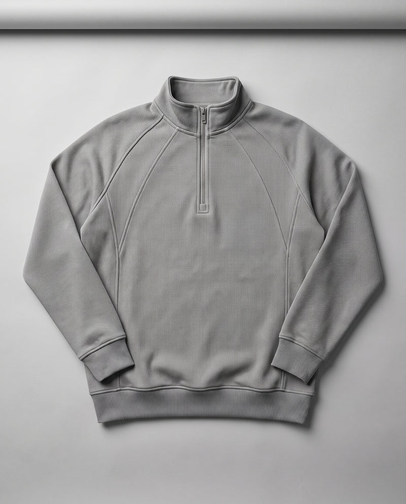 Sweat gris à demi-zip présenté à plat, entièrement déplié, avec col montant et fermeture éclair.