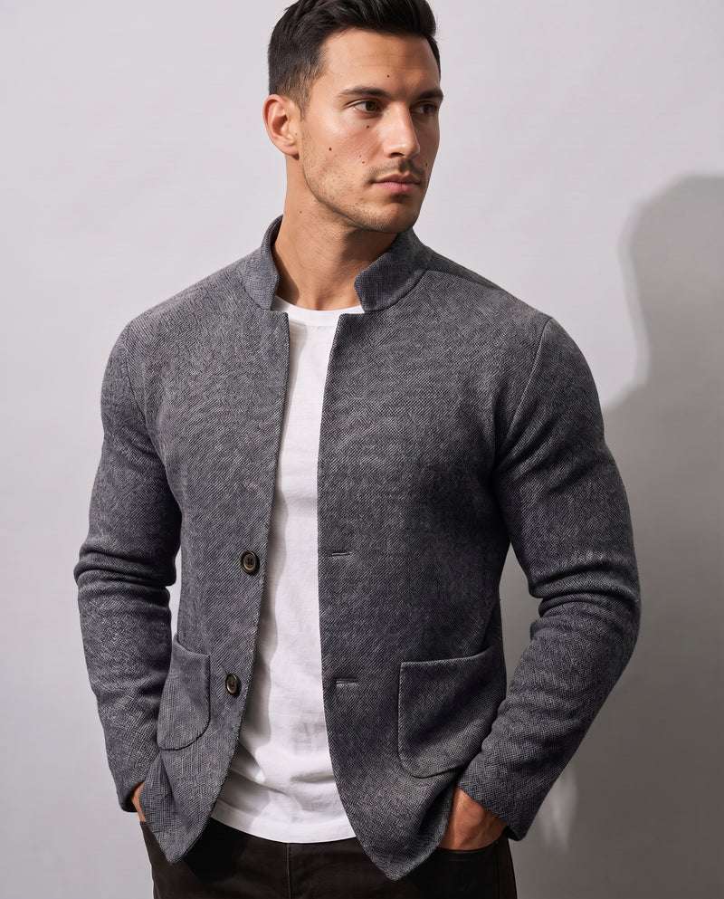Veste en maille texturée grise pour homme, portée ouverte sur un tee-shirt blanc, vue buste-hanches, fermeture à deux boutons, col montant, deux poches plaquées au niveau des hanches.
