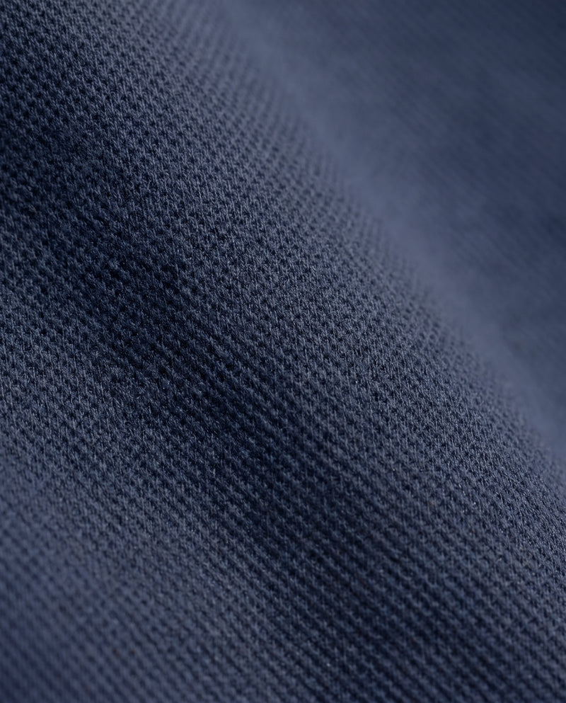 Gros plan sur la texture gaufrée du tissu du sweat bleu marine à demi-zip.