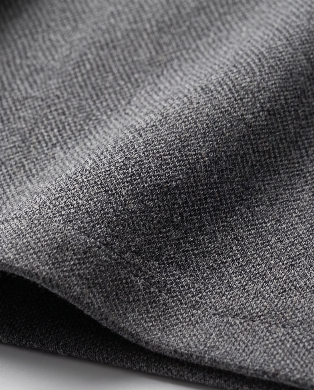 Gros plan sur le tissu en maille de la veste grise.