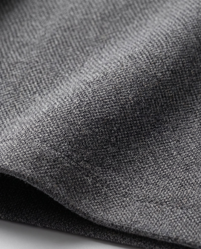 Gros plan sur le tissu en maille de la veste grise.
