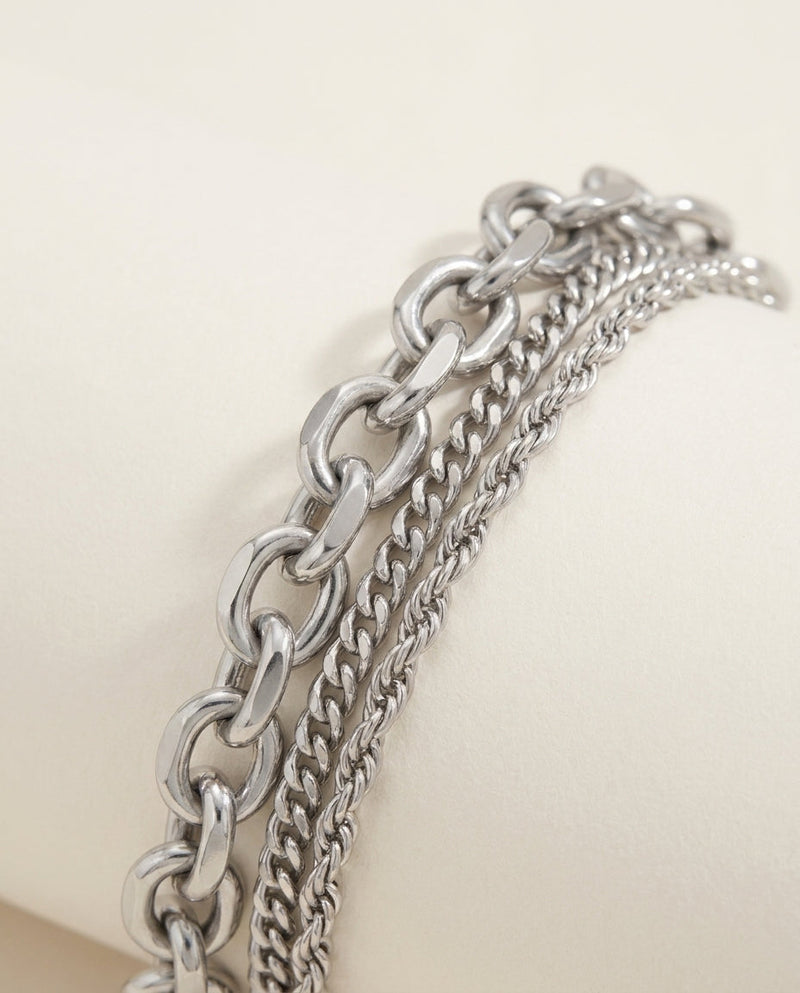 Gros plan sur le maillon épais et les chaînes fines d'un bracelet argenté