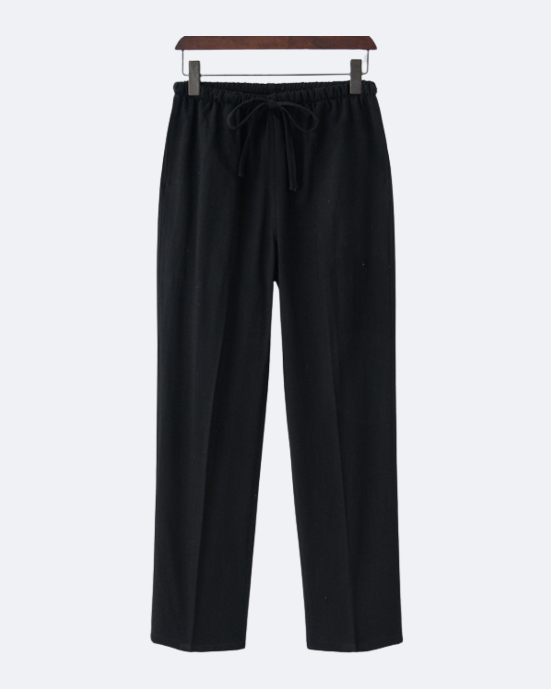 Black drawstring trousers on a wooden hanger, front view