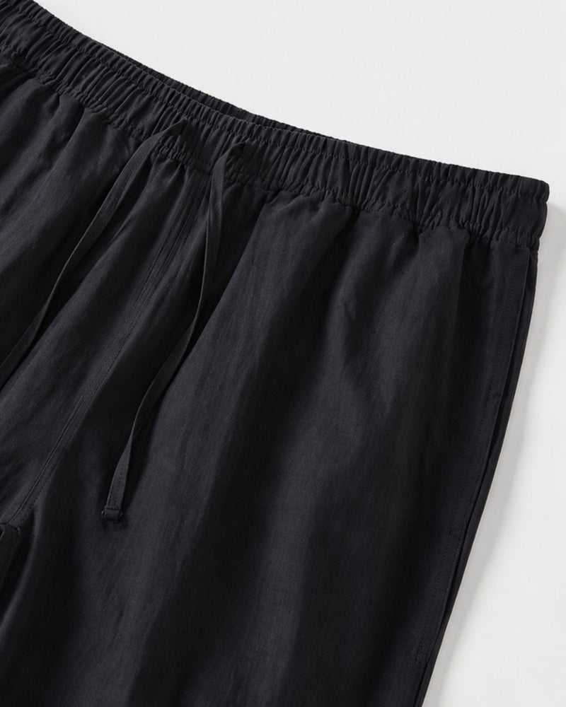 Gros plan sur la taille élastiquée et le cordon de serrage du pantalon noir