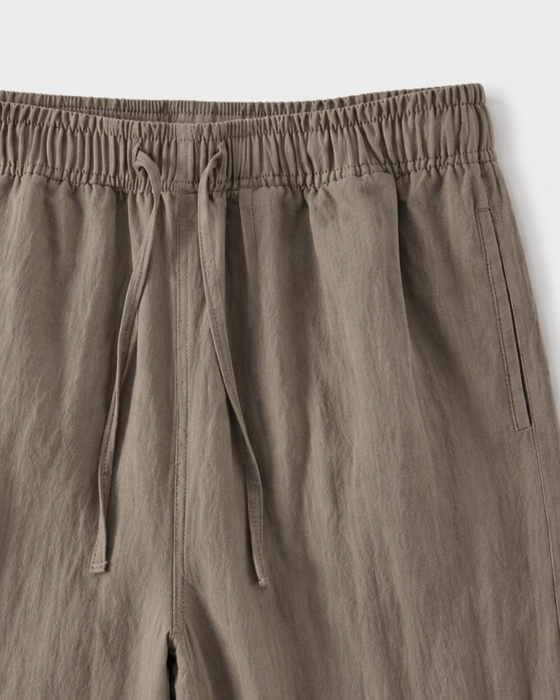 Gros plan sur la taille à cordon de serrage et la poche latérale du pantalon kaki