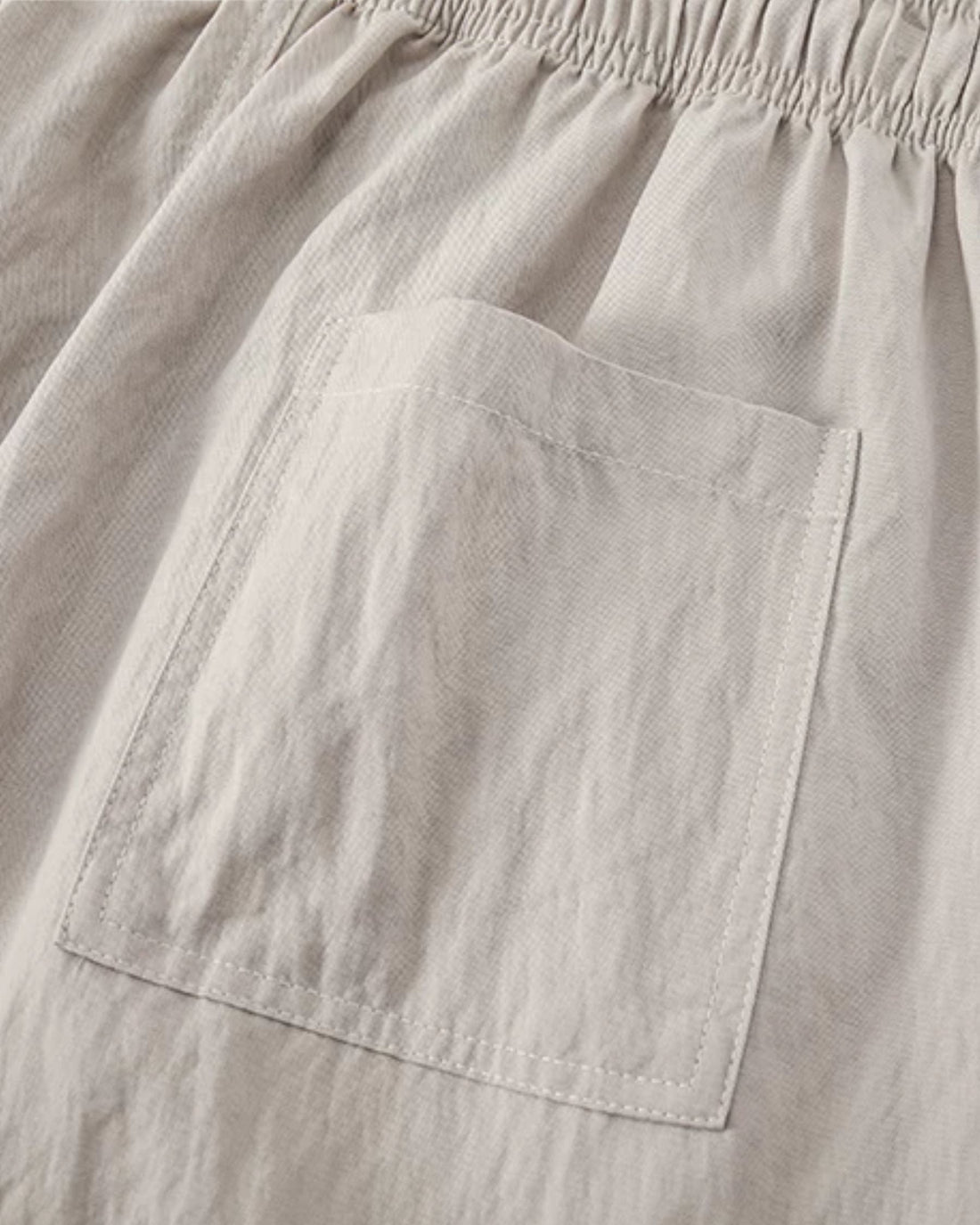 Close-up of the cream trousers' patch pocket and textured weave