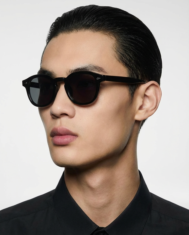 Homme portant des lunettes de soleil à monture ronde noire à verres foncés, vue de trois quarts