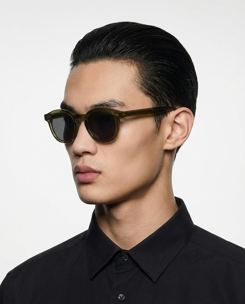 Homme portant des lunettes de soleil à monture ronde olive à verres foncés, vue de profil
