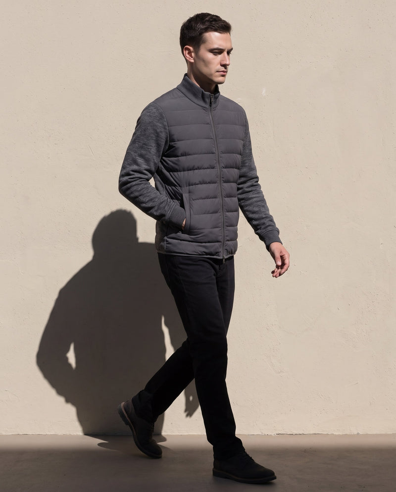 Bellardi Hybrid Puffer Jacket in Dark Grey, full-length view worn while walking, showing the quilted front panel, knit sleeves and hem.