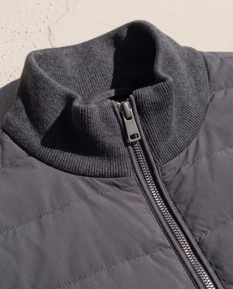Close-up of the Bellardi Hybrid Puffer Jacket's ribbed knit collar and centre-front zip pull in Dark Grey.