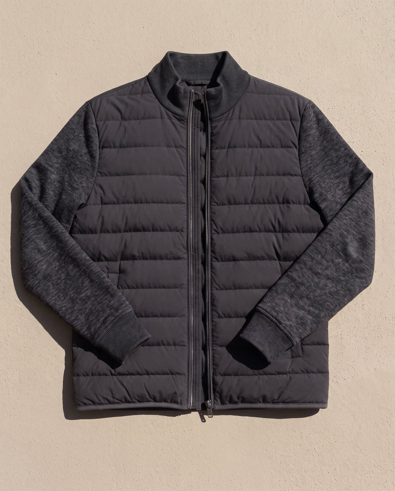Bellardi Hybrid Puffer Jacket in Black, laid flat and unzipped, showing the quilted front panel, knit sleeves and collar.