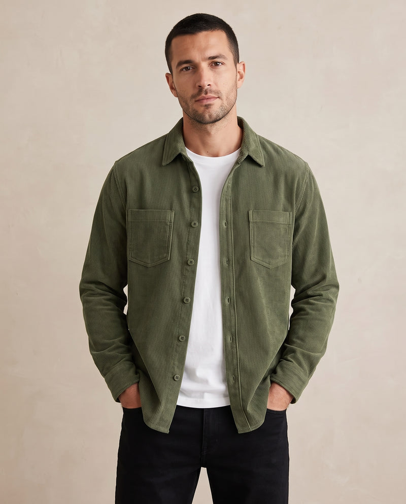 Homme portant une surchemise en velours côtelé vert armée ouverte sur un t-shirt blanc, mains dans les poches