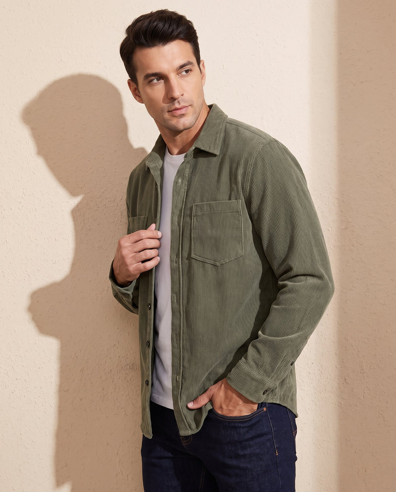 Man wearing an army green corduroy overshirt, three-quarter view, one hand on the front placket