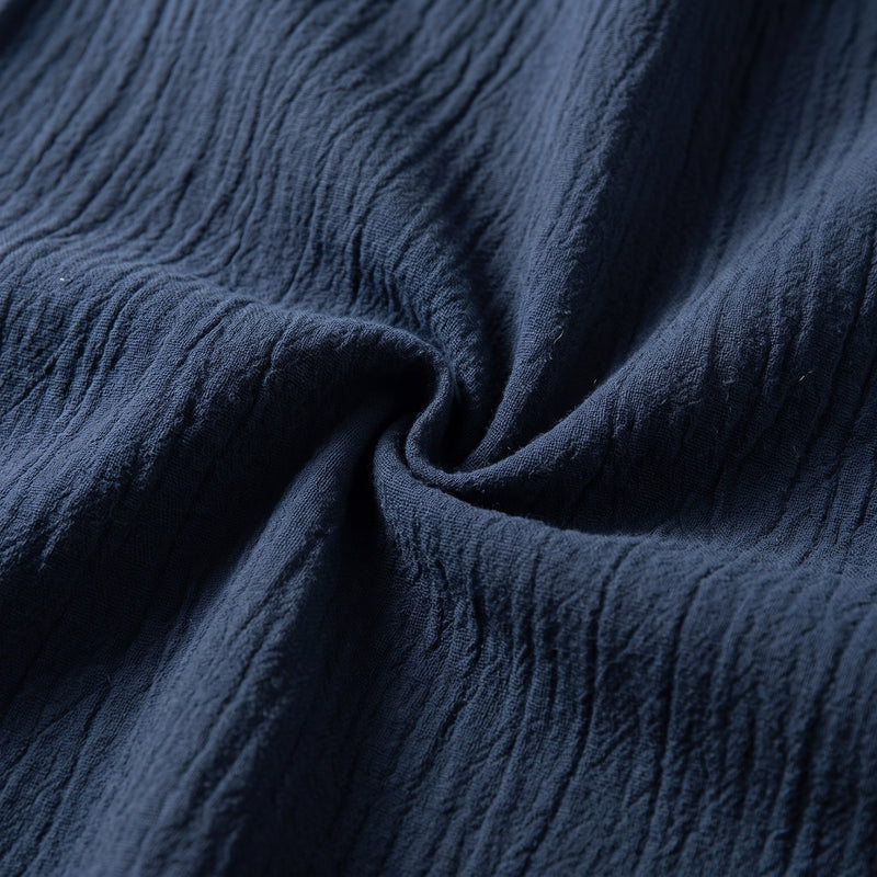 Gros plan sur le tissage froissé bleu marine du pantalon, texture verticale fine visible.