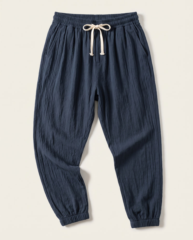 Pantalon confort bleu marine à plat, vue de face, tissage froissé et cordon de serrage écru à la taille.