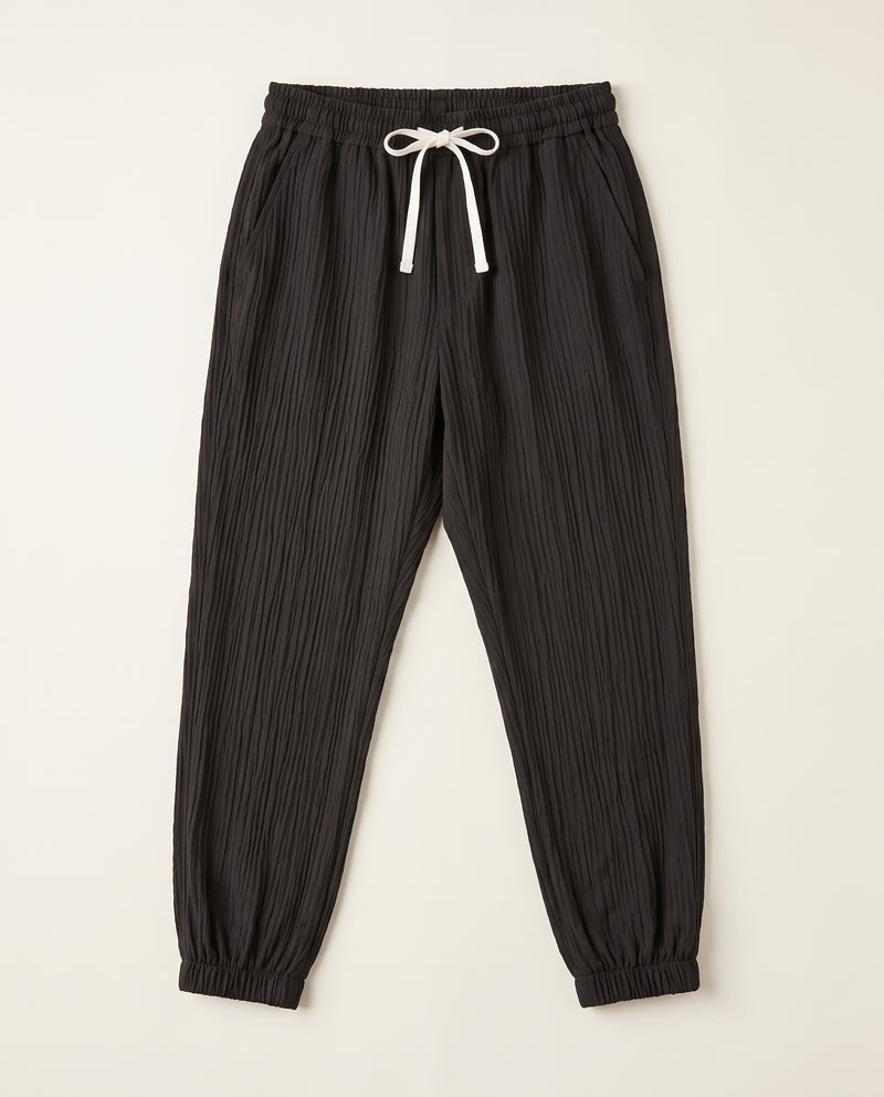 Pantalon confort noir à plat, vue de face, tissage froissé et cordon de serrage blanc à la taille.