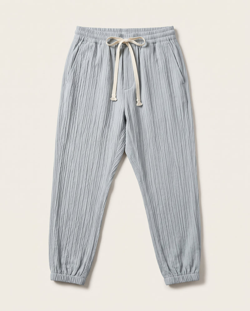 Pantalon confort bleu clair à plat, vue de face, tissage froissé et cordon de serrage écru à la taille.
