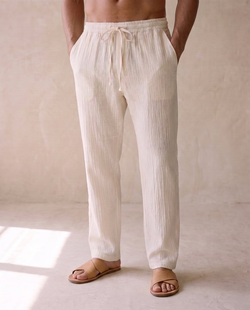 Pantalon ample écru à cordon de serrage porté avec des sandales en cuir fauve, bas du corps