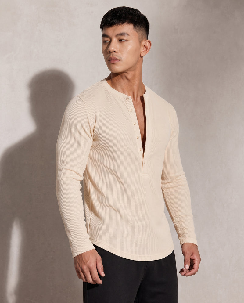 Pull Kade en maille côtelée écru, vue trois quarts, patte de boutonnage à six boutons tonals et boîte de fermeture rectangulaire visibles.