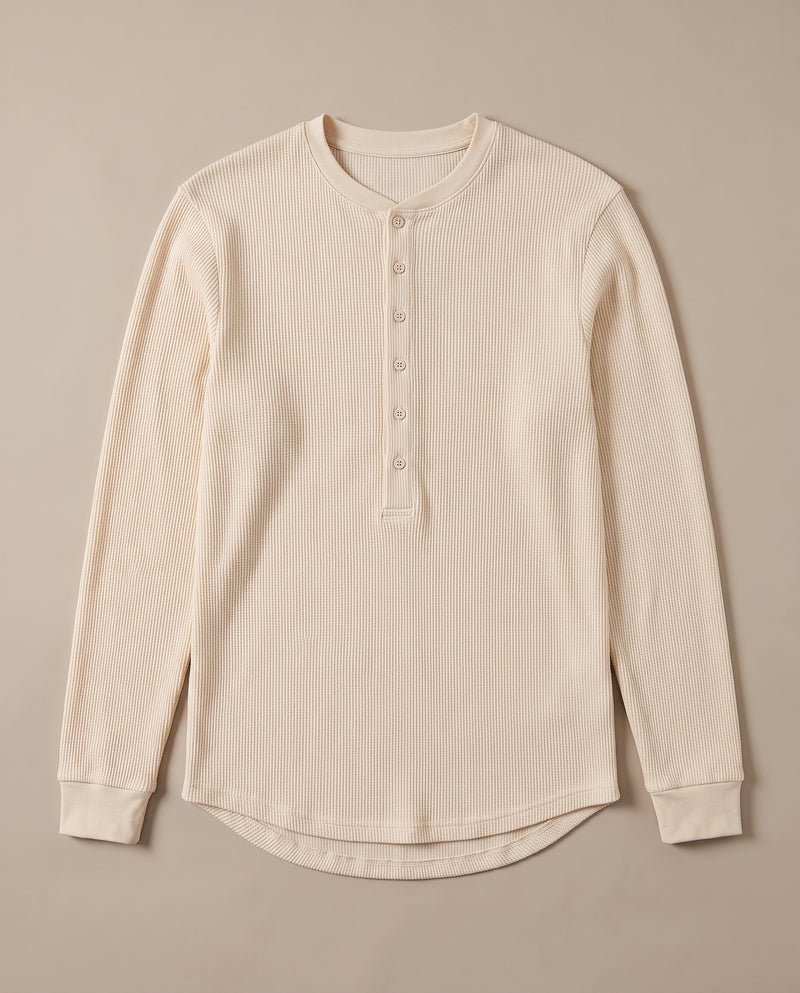 Pull Kade en maille côtelée écru à plat, déplié, montrant l'encolure ronde côtelée, la demi-patte de boutonnage et l'ourlet arrondi.