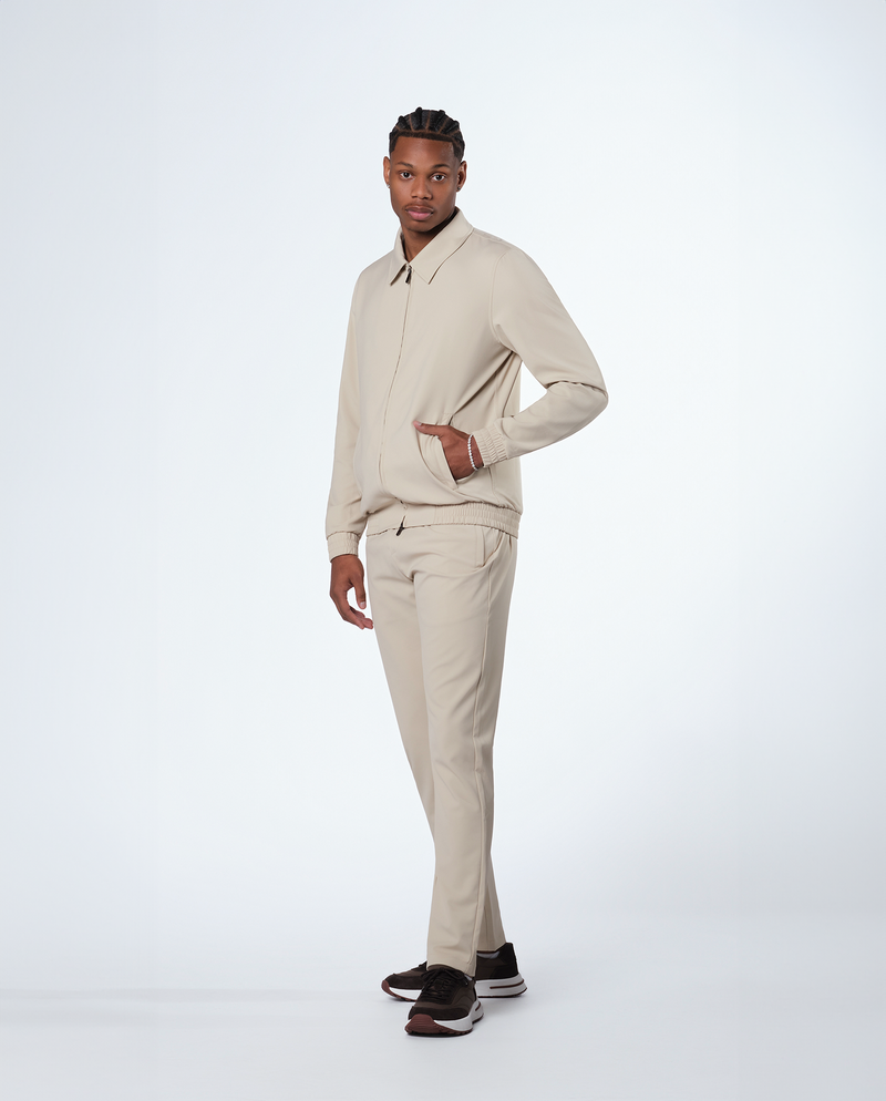 Homme portant un pantalon beige avec la veste zippée assortie, vue de profil en pied