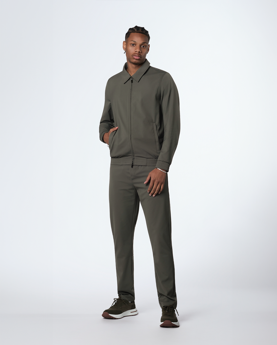 Man wearing an olive-green zip jacket and matching trousers, full length side view