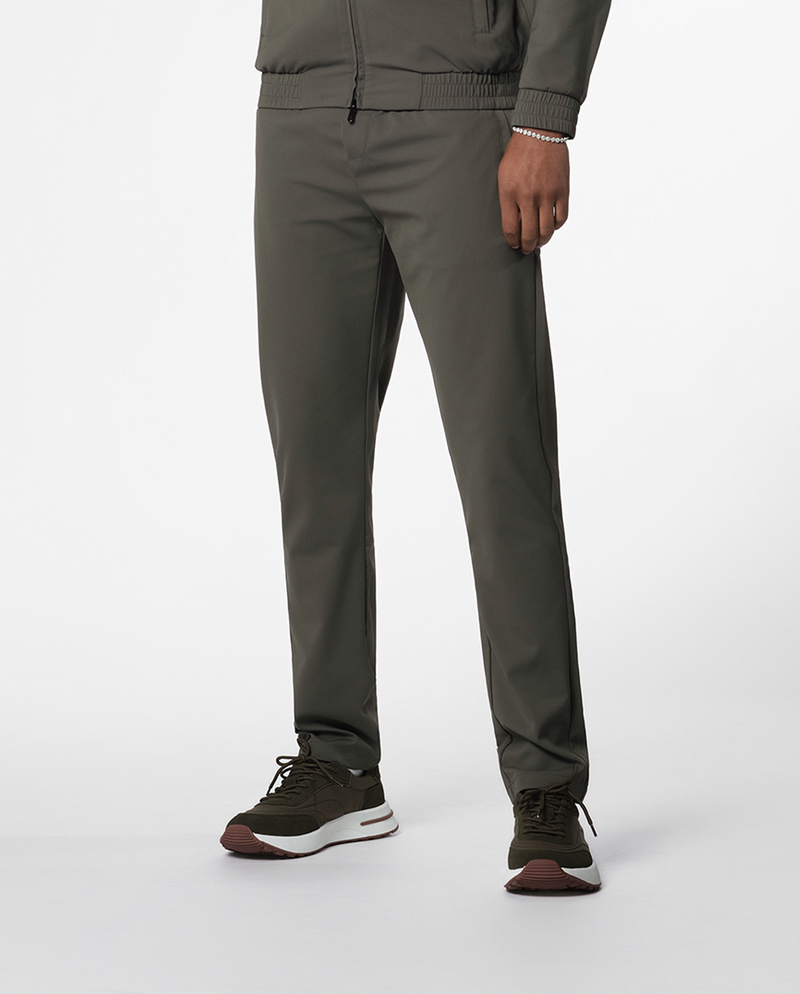 Pantalon fuselé vert olive porté avec des baskets foncées, bas du corps