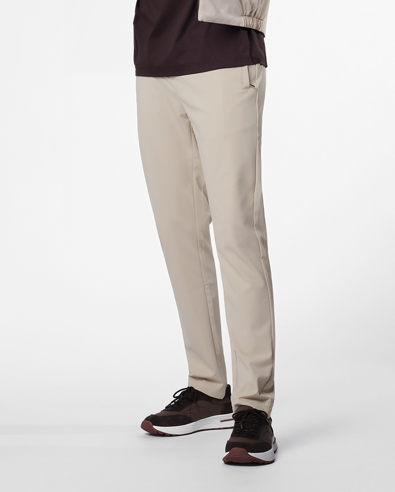 Pantalon fuselé beige porté avec des baskets foncées, bas du corps